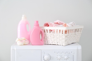 Photo of Bottles of detergent and children's clothes on washing machine