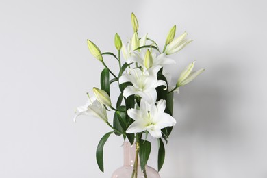 Photo of Beautiful bouquet of lily flowers in glass vase on white background