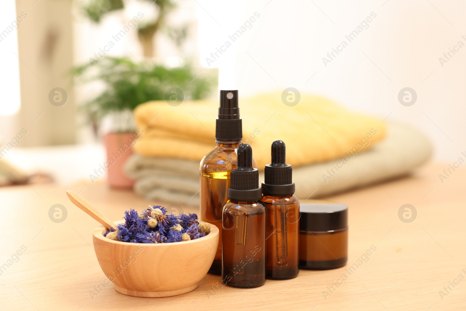 Photo of Dry flowers, bottles of essential oils and jar with cream on wooden table indoors. Spa time