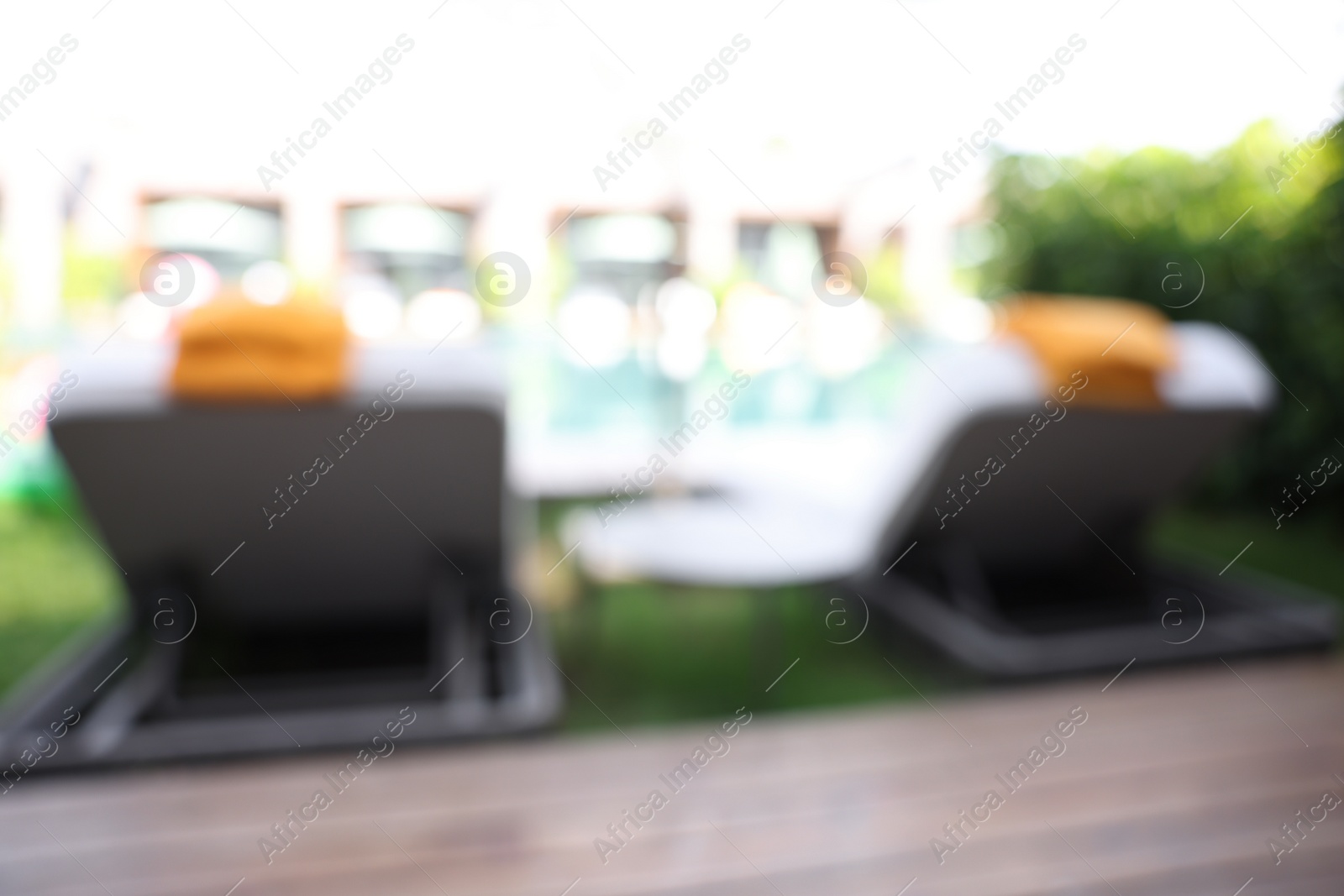 Photo of Sunbeds near swimming pool at luxury resort, blurred view