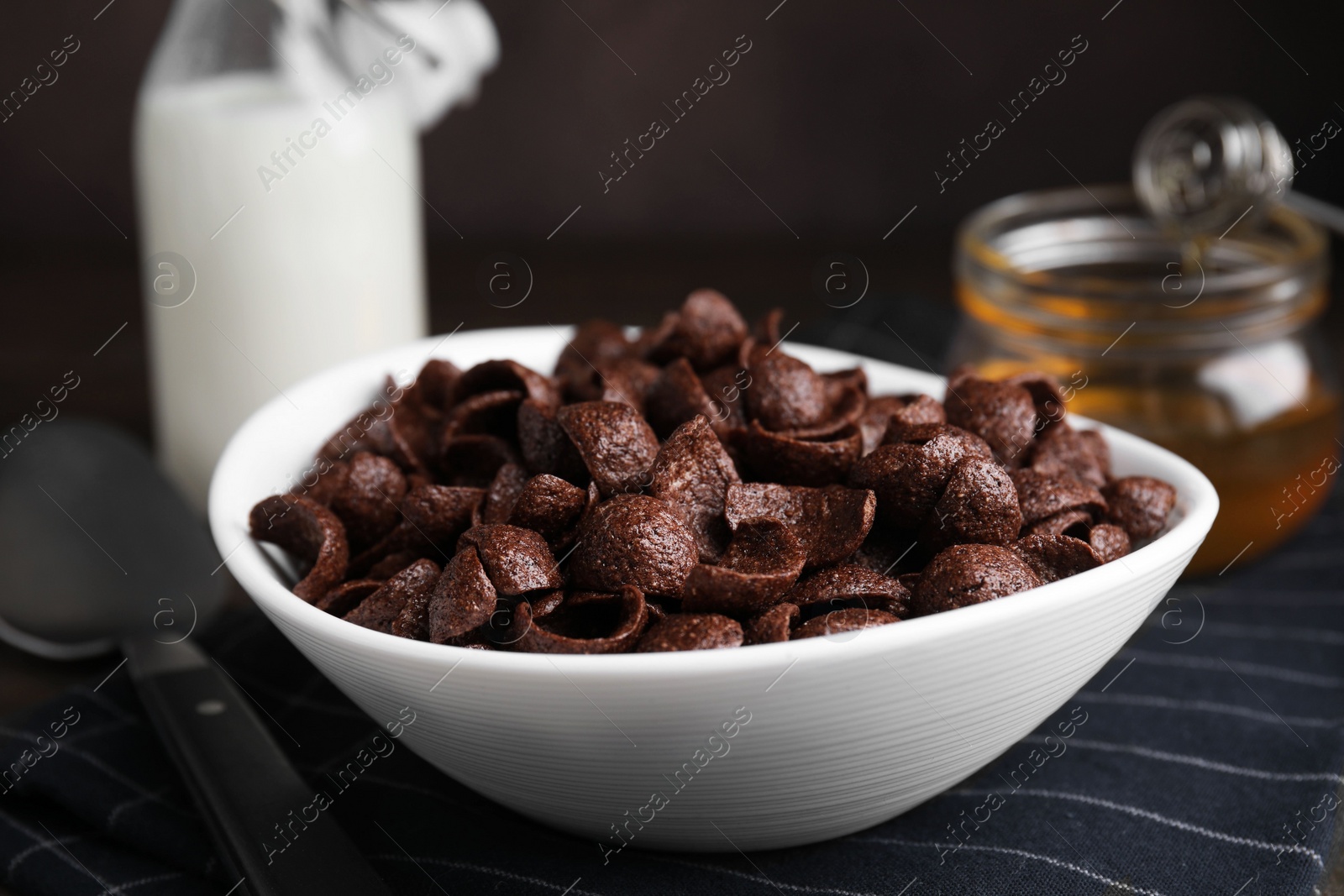 Photo of Breakfast cereal. Chocolate corn flakes in bowl on table, closeup