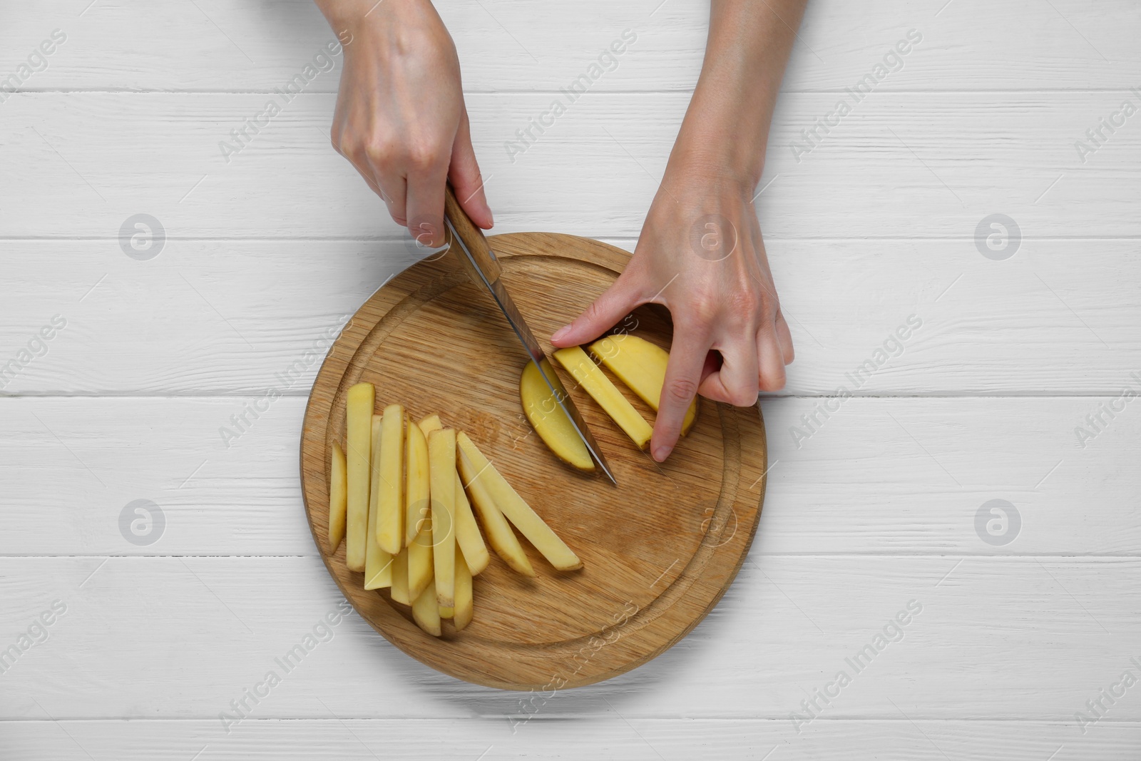 Photo of Woman cut potatoes on white wooden table, top view