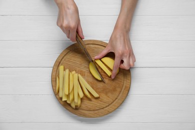 Photo of Woman cut potatoes on white wooden table, top view