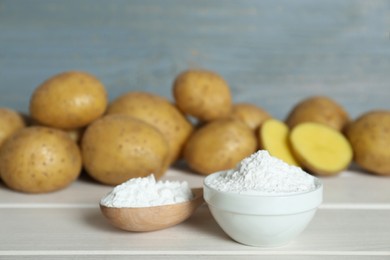 Starch and fresh raw potatoes on white wooden table. Space for text