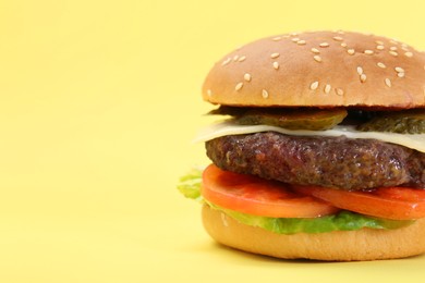 Photo of Burger with delicious patty on yellow background, closeup. Space for text