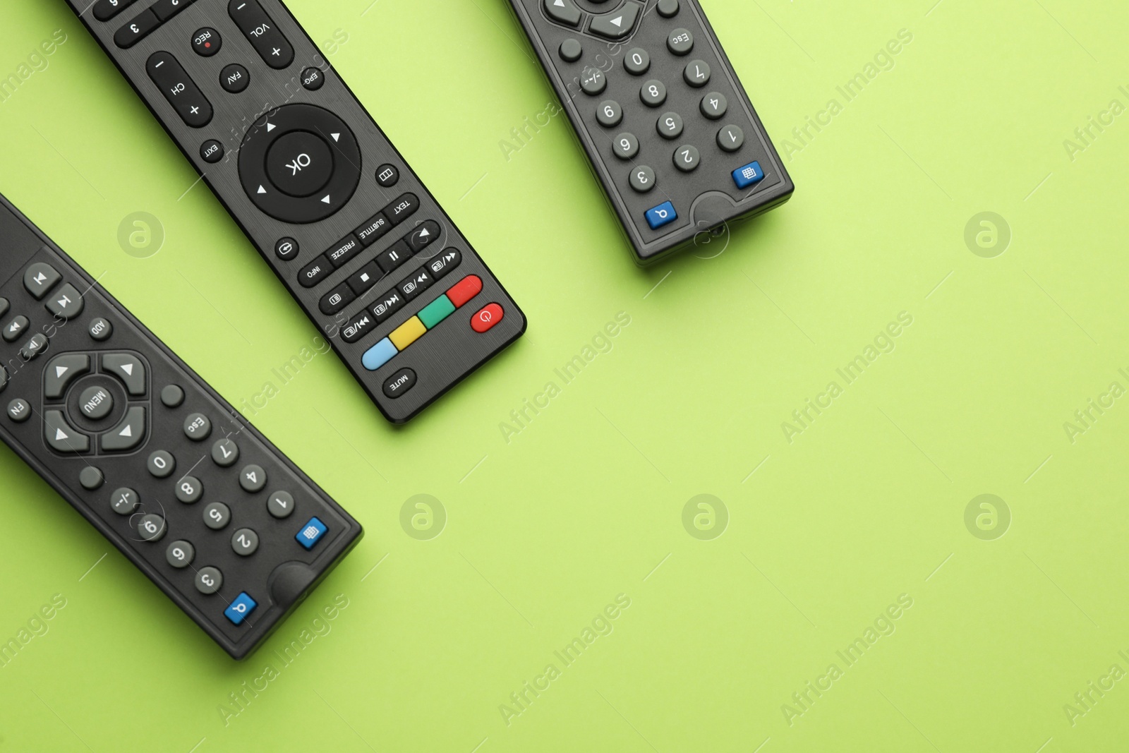 Photo of Remote controls on light green background, flat lay. Space for text