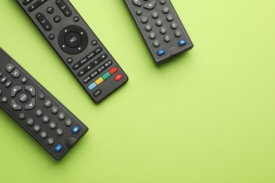 Photo of Remote controls on light green background, flat lay. Space for text