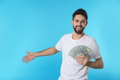 Photo of Portrait of happy young man with money on color background. Space for text