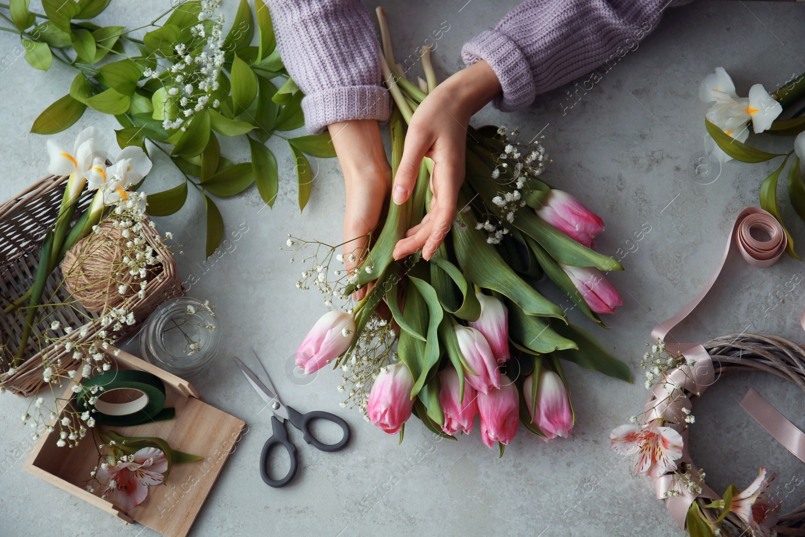 Photo of Female decorator creating beautiful bouquet at table