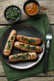 Tasty fresh grilled sausages served with sauces on wooden table, flat lay