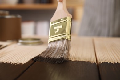 Photo of Applying wood stain onto wooden surface indoors, closeup