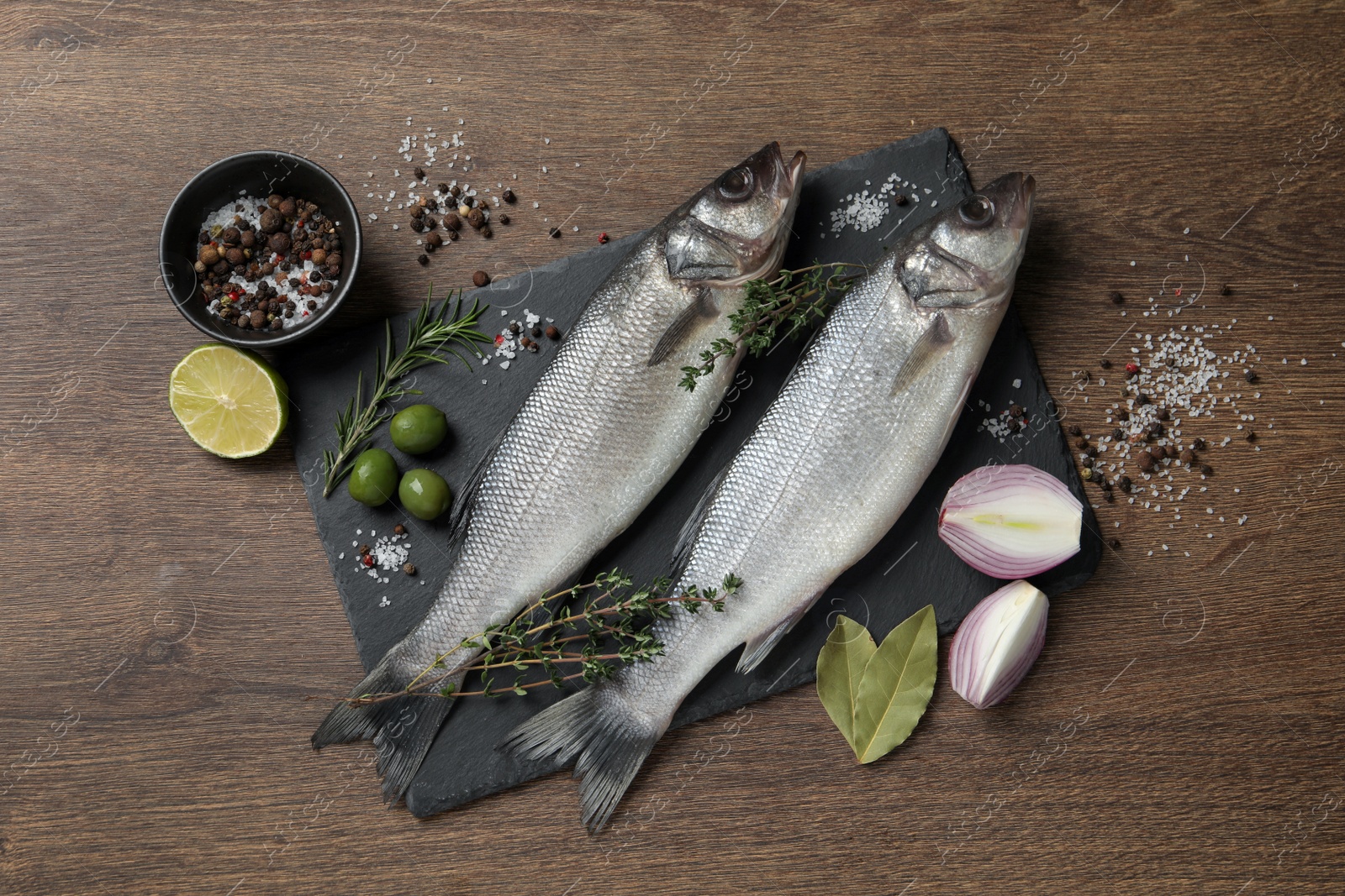 Photo of Sea bass fish and ingredients on wooden table, flat lay