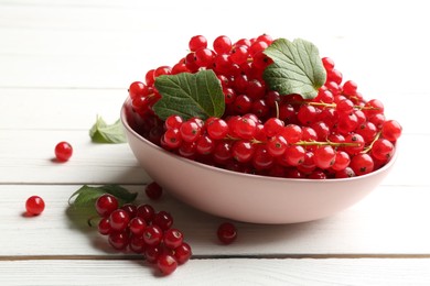 Delicious red currants and leaves on white wooden table