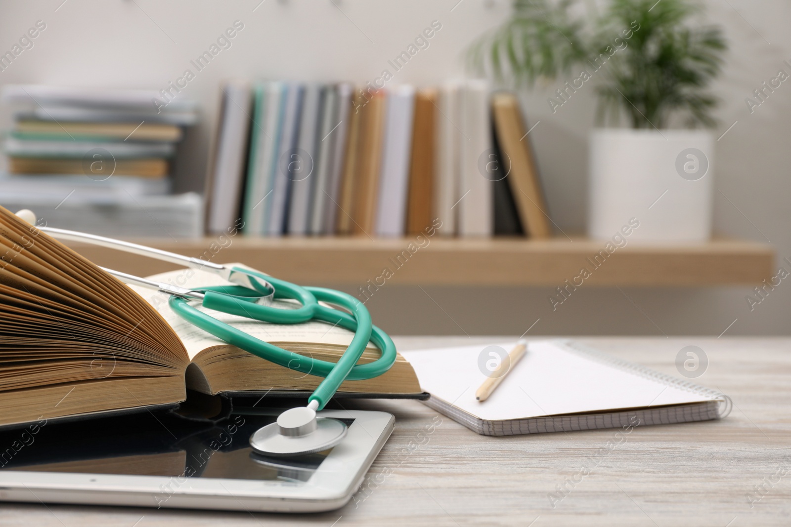 Photo of Book, tablet and stethoscope on wooden table indoors, space for text. Medical education