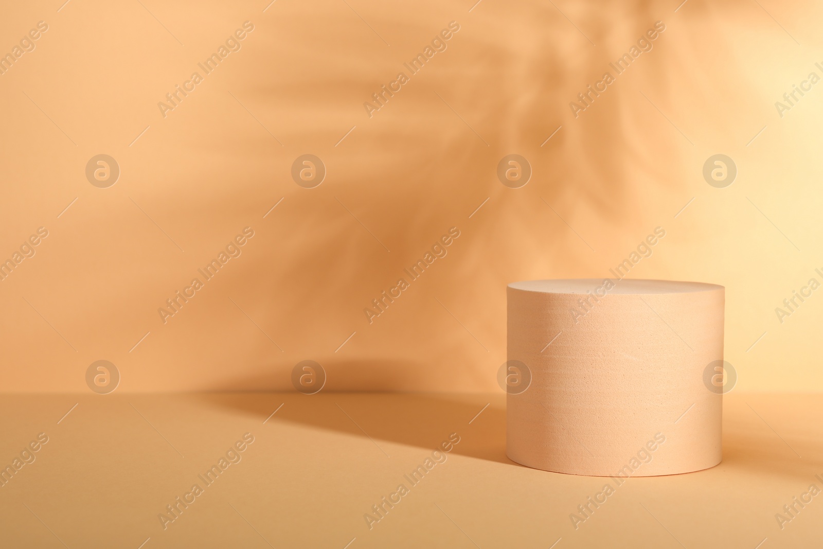 Photo of Presentation of product. Podium and shadows on orange background. Space for text