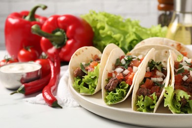 Photo of Delicious tacos with meat and vegetables on white table, closeup