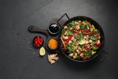 Stir-fry. Tasty noodles with meat in wok and ingredients on grey textured table, flat lay