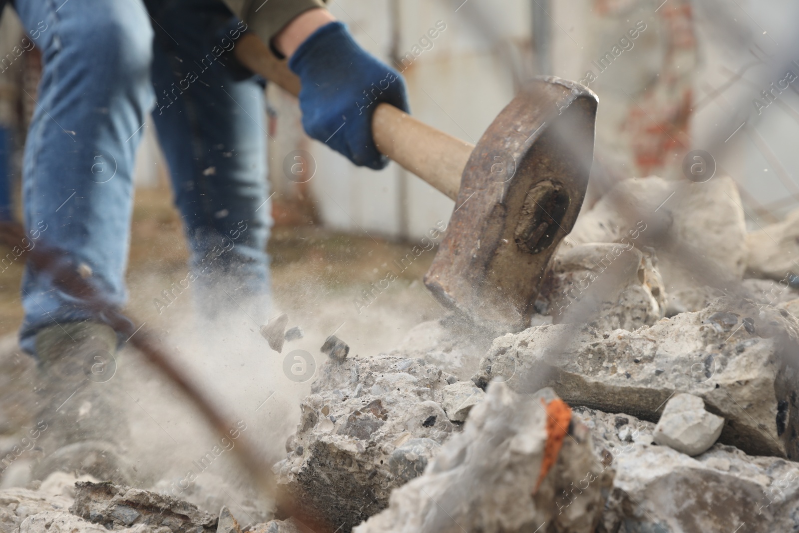 Photo of Man breaking stones with sledgehammer outdoors, closeup