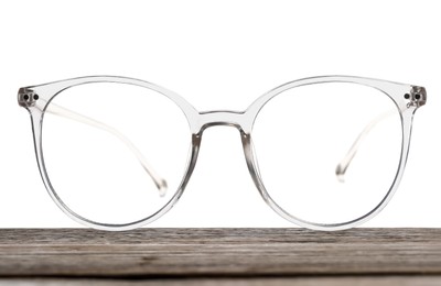 Photo of Stylish glasses with transparent frame on wooden table against white background