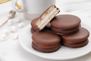 Photo of Saucer with delicious choco pies on white table, closeup