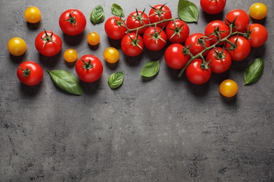 Flat lay composition with ripe cherry tomatoes and basil leaves on color background. Space for text