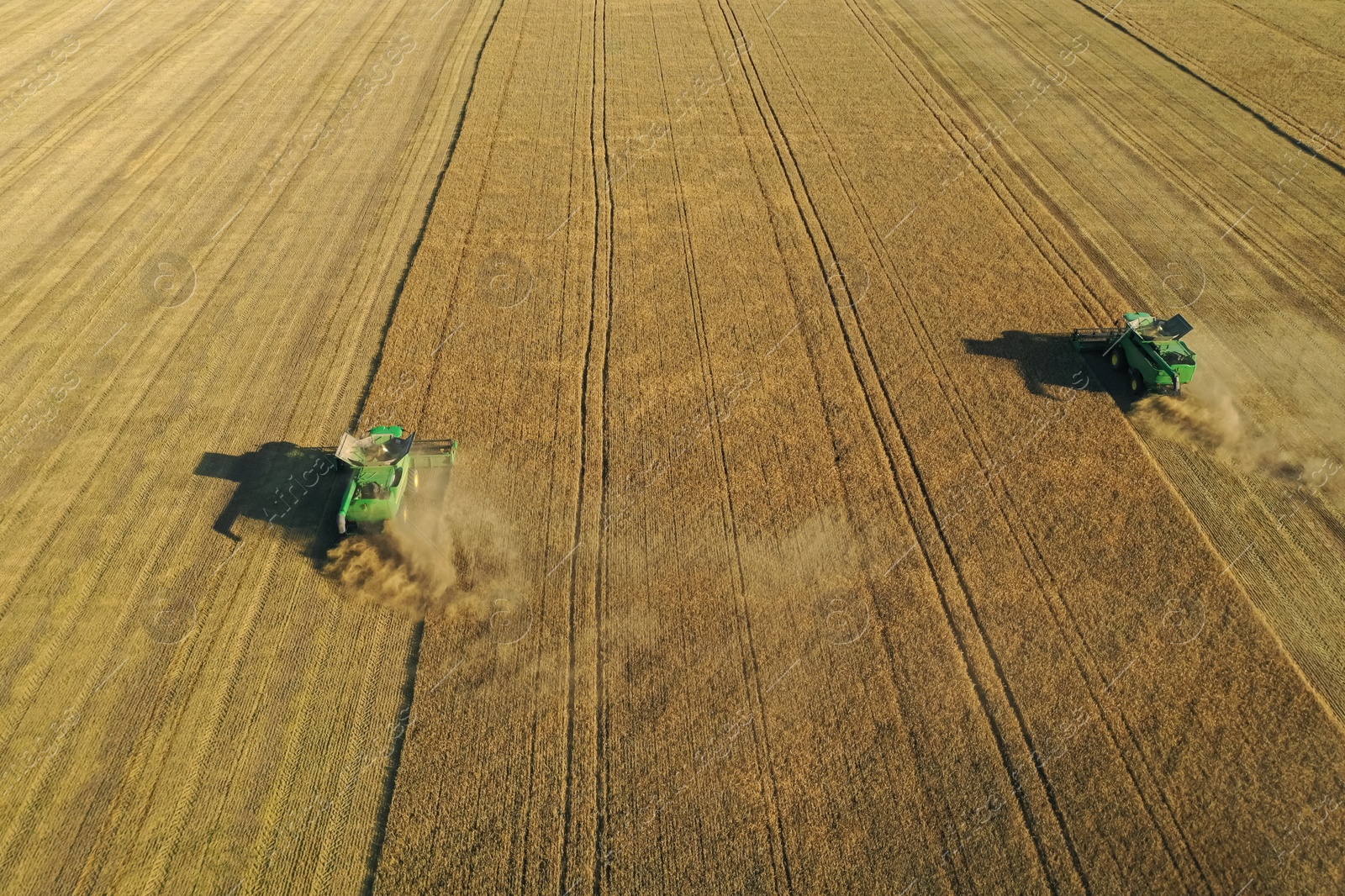 Photo of Beautiful aerial view of modern combine harvesters working in field on sunny day. Agriculture industry