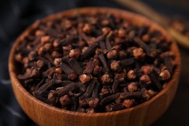Photo of Aromatic cloves in bowl on table, closeup