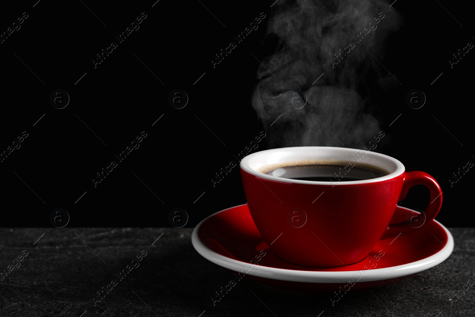 Image of Red cup with hot steaming coffee on dark table against black background, space for text