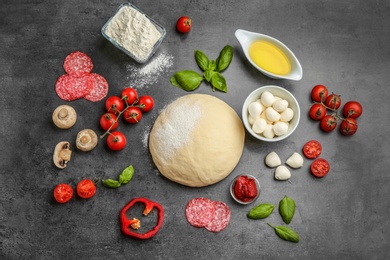 Photo of Flat lay composition with raw dough and ingredients for pizza on grey background