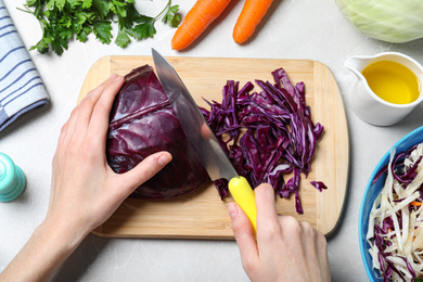 Photo of Woman cutting red cabbage at light grey marble table, top view