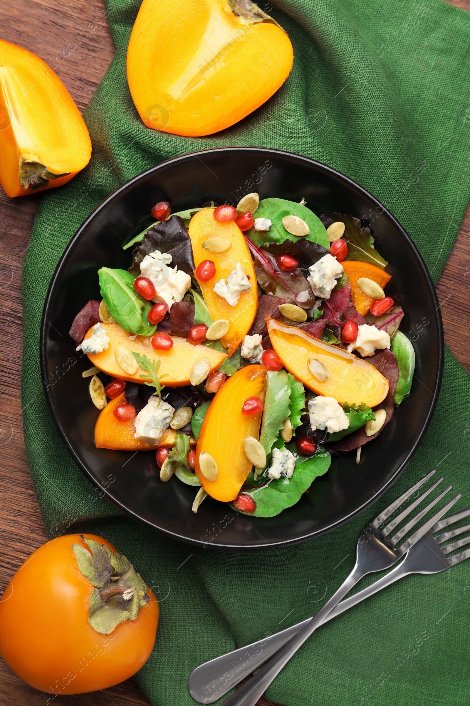 Photo of Delicious persimmon salad and forks on wooden table, flat lay