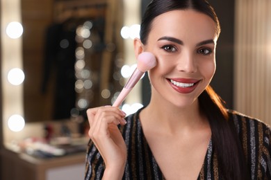 Photo of Bright makeup. Beautiful woman applying face powder in dressing room, space for text