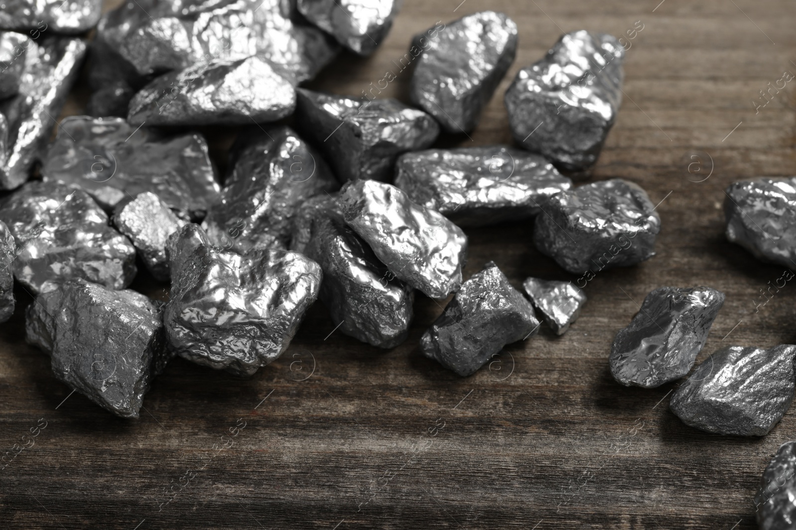 Photo of Pile of silver nuggets on wooden table, closeup