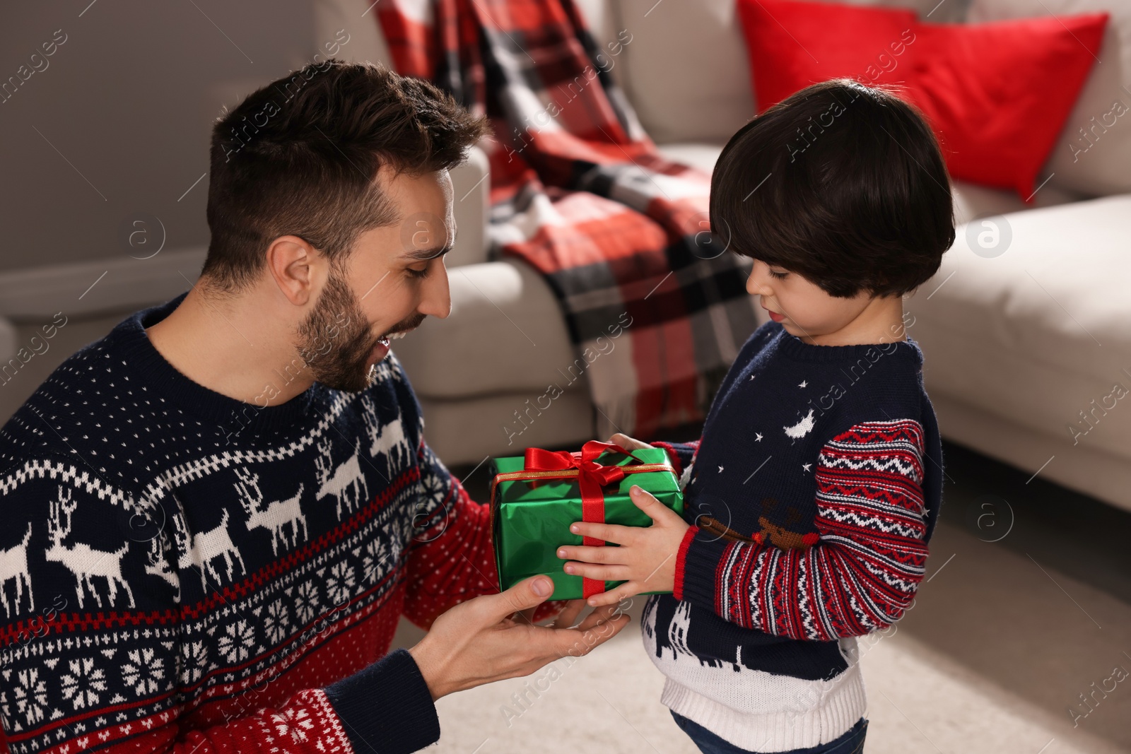 Photo of Cute son giving present to his father at home. Christmas celebration