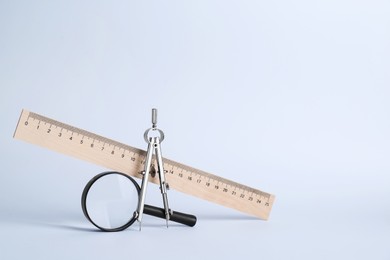 Ruler, magnifying glass and compass on white background