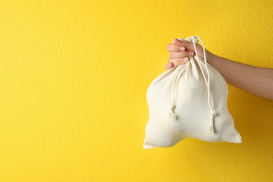Photo of Woman holding full cotton eco bag on yellow background, closeup. Space for text