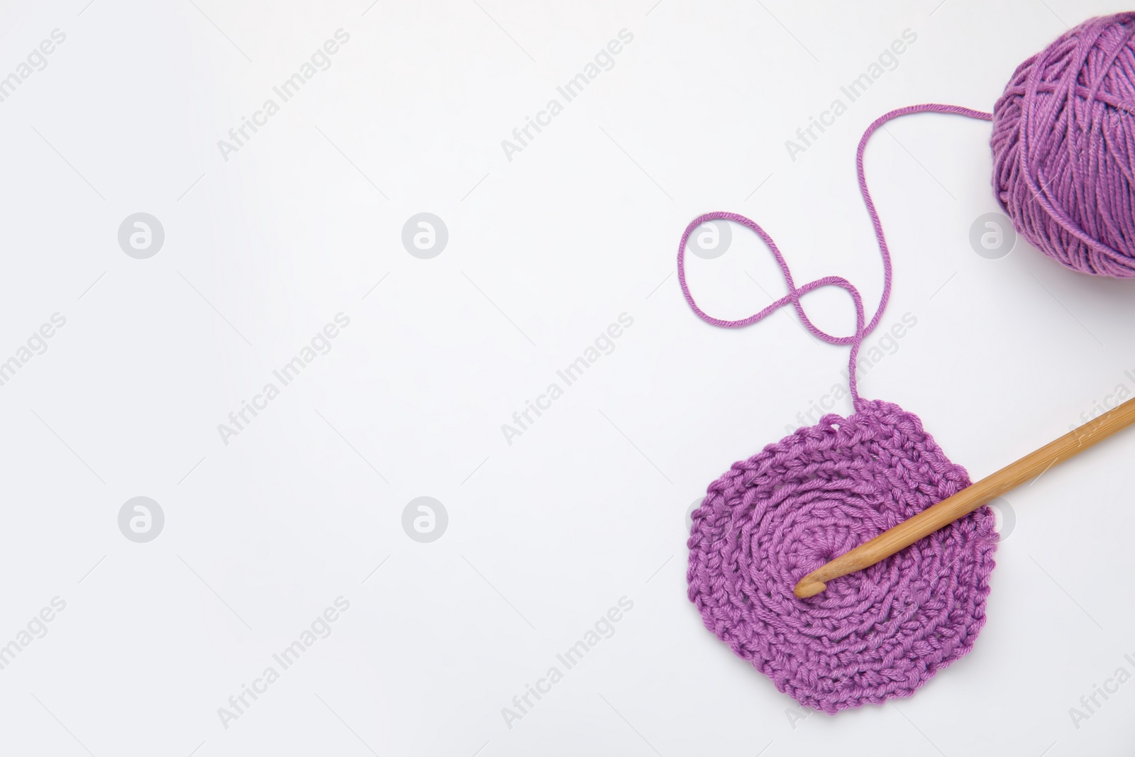 Photo of Soft violet woolen yarn, knitting and crochet hook on white background, top view