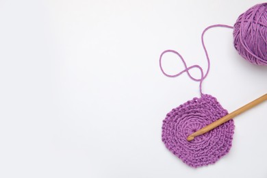 Photo of Soft violet woolen yarn, knitting and crochet hook on white background, top view