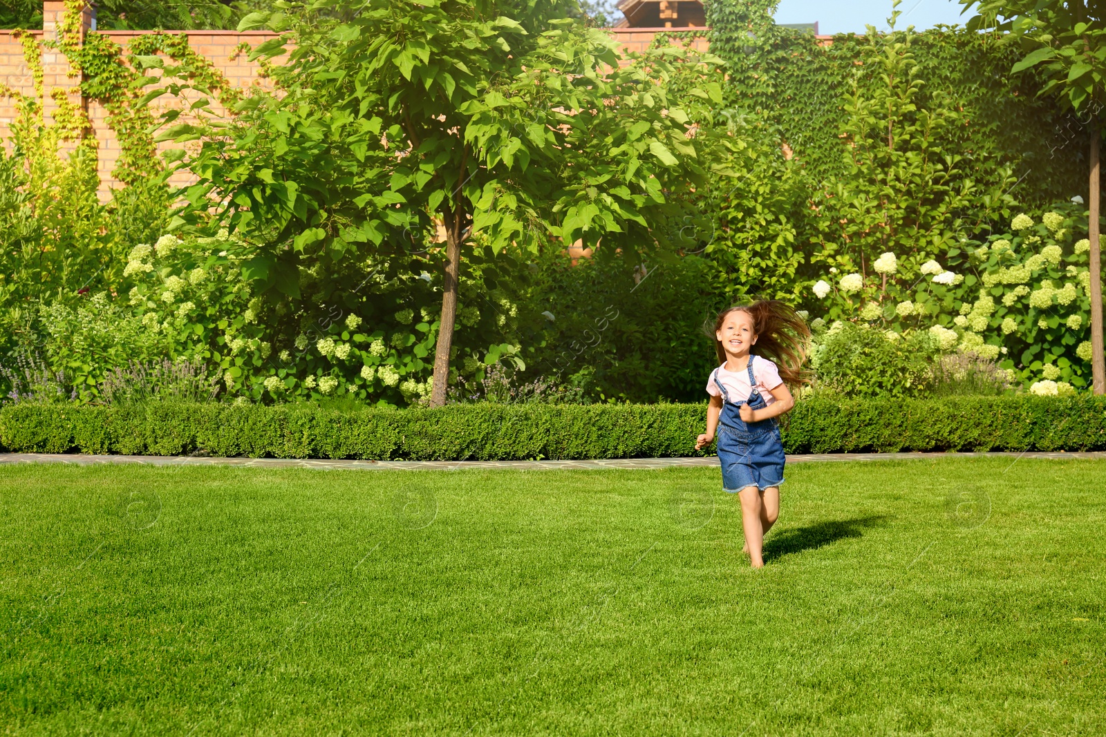 Photo of Cute little girl running in green park on summer day