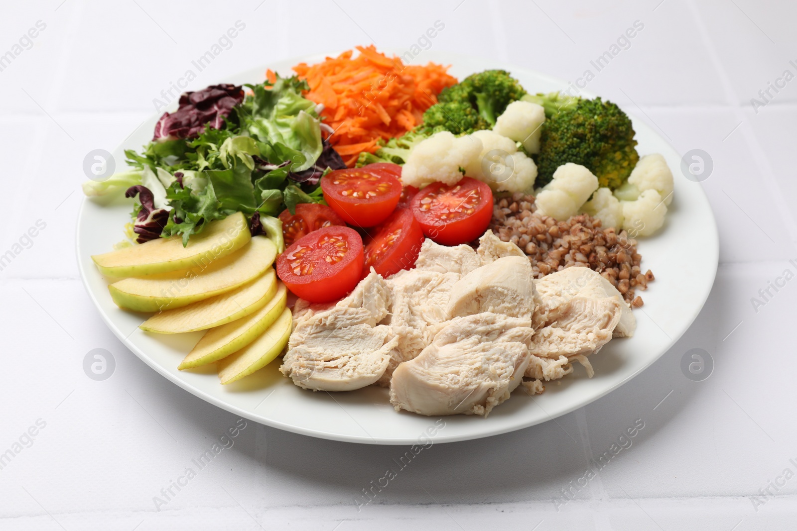 Photo of Balanced diet and healthy foods. Plate with different delicious products on white tiled table