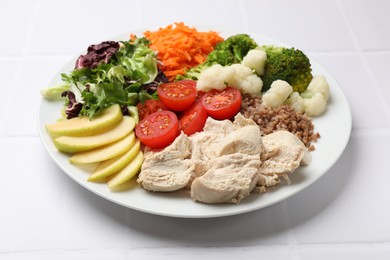 Balanced diet and healthy foods. Plate with different delicious products on white tiled table