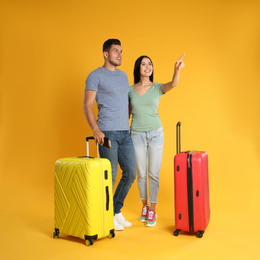 Photo of Happy couple with suitcases for summer trip on yellow background. Vacation travel