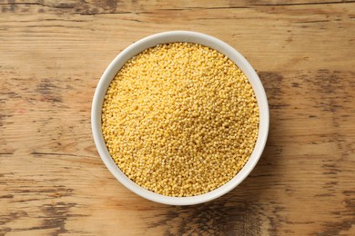 Photo of Millet groats in bowl on wooden table, top view