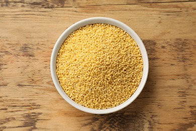 Millet groats in bowl on wooden table, top view