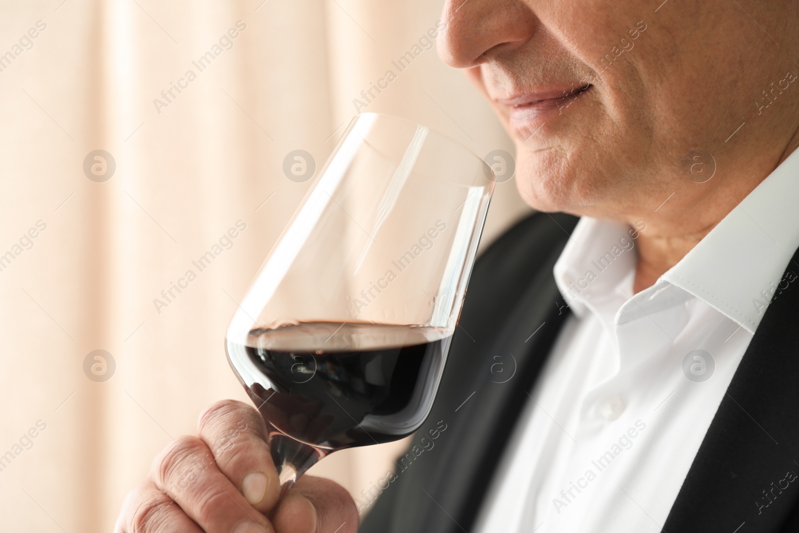 Photo of Senior man with glass of wine indoors, closeup