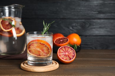 Photo of Delicious refreshing drink with sicilian orange and rosemary on wooden table. Space for text