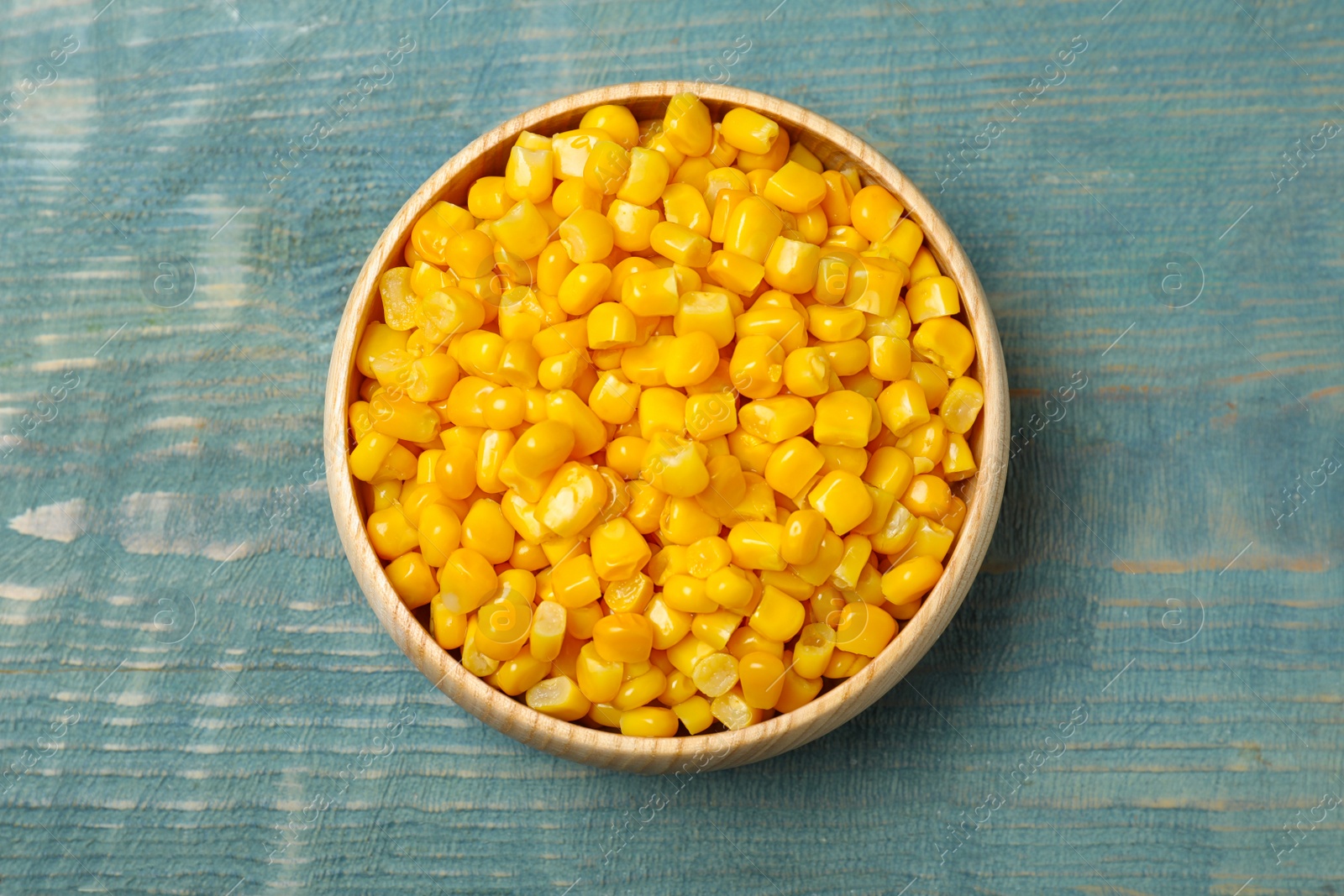 Photo of Tasty canned sweet corn on blue wooden table, top view