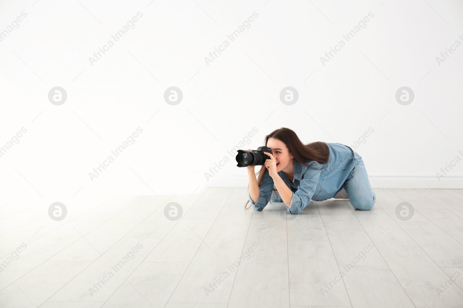 Photo of Female photographer with camera lying on floor indoors