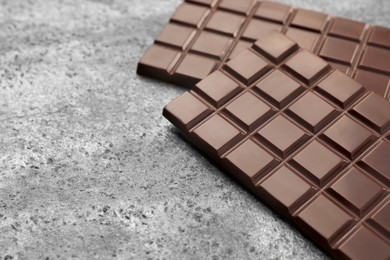 Delicious dark chocolate bars on grey table, closeup. Space for text