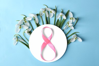 Photo of Beautiful snowdrops, paper card and number 8 made of ribbon on pink background, flat lay